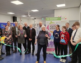 A ribbon being cut by a female at the reopening of a Young People's Centre. 