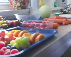 A selection of fruit and carrots on a stainless steel worktop in a kitchen