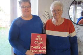 Shelley and Lyn holding a sign that says keep calm and carry on fostering