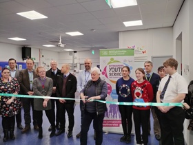 A ribbon being cut by a female at the reopening of a Young People's Centre. 