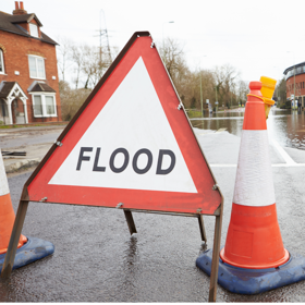 A flooding sign next to a traffic cone and flood waters