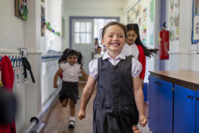 Three young school children running in a school corridor.